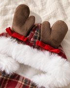 A close-up of a holiday-themed plush accessory with two brown reindeer antlers, red velvet bows, and white faux fur trim over a red plaid fabric, laid on a textured off-white fabric background.